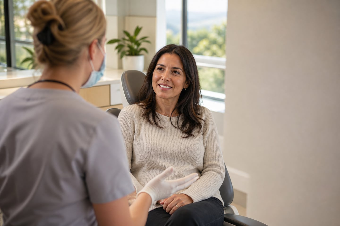 A dentist and patient talking together in a bright consulting room before an appointment.